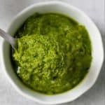 A spoonful of parsley pesto served from a white bowl