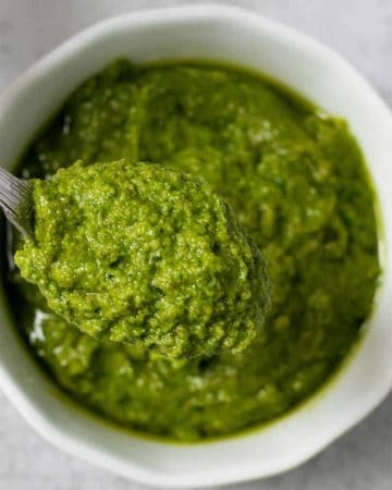 A spoonful of parsley pesto served from a white bowl