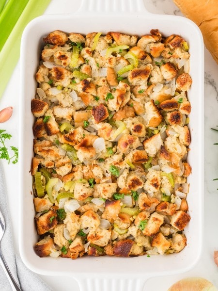 Homemade Stuffing in a white baking dish made with toasted bread cubes, celery, onions, and fresh herbs.