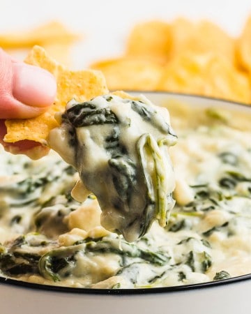 A bowl of creamy Spinach Dip with Nachos chips for dipping.