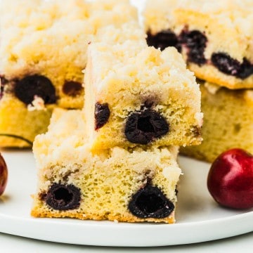 Slices of freshly baked Cherry Crumb Cake on a white plate.