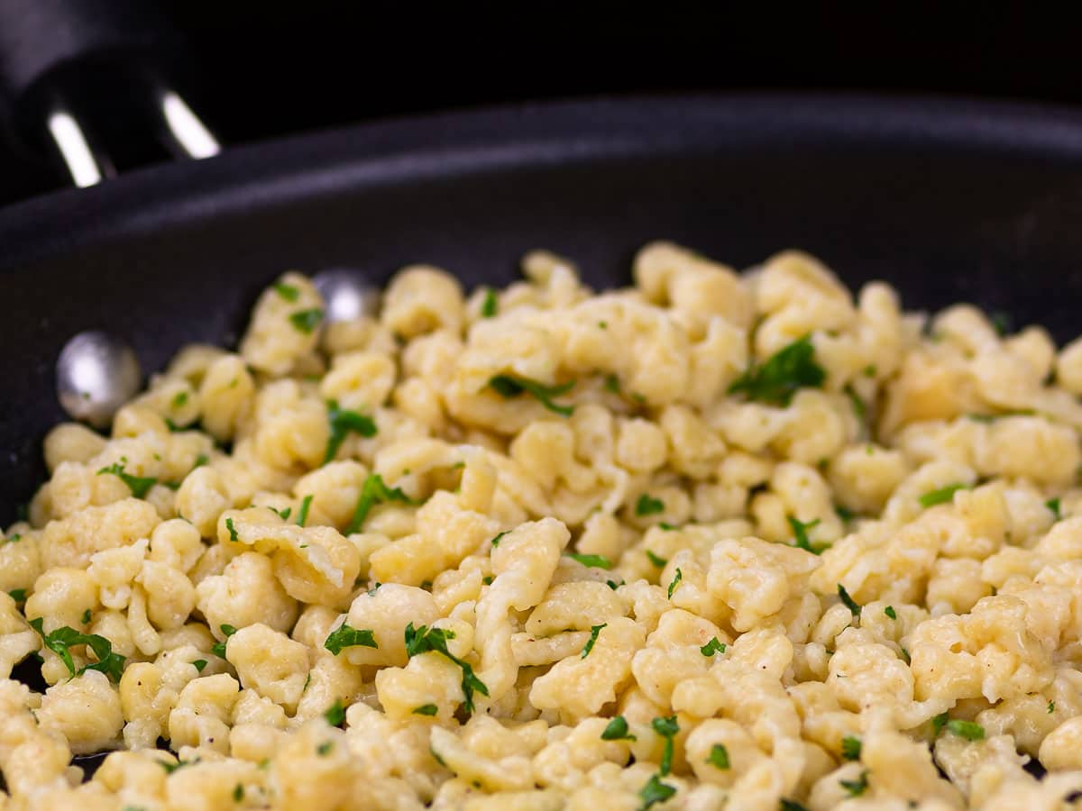 Sautéing freshly cooked spaetzle (German egg noodles) in a frying pan with butter