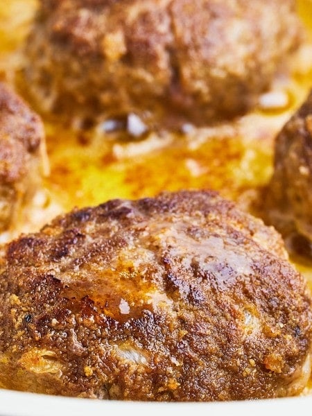 Closeup of cooked Frikadellen in a frying pan.