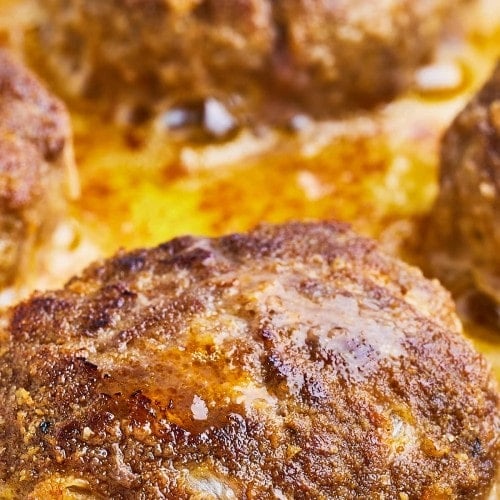 Closeup of cooked Frikadellen in a frying pan.
