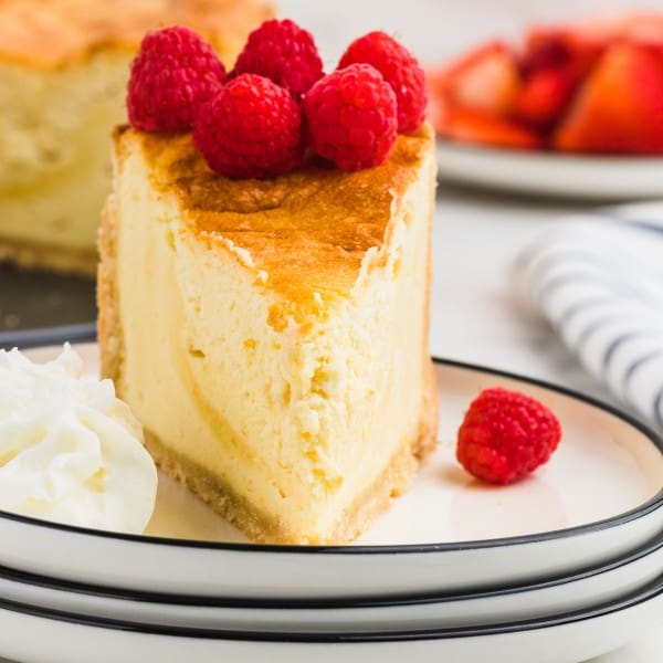 A slice of German Cheesecake (Käsekuchen) with fresh berries on a white plate.