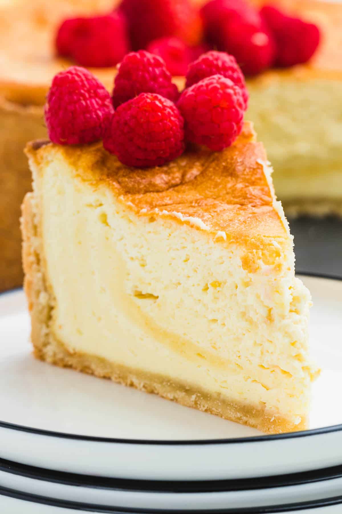 Closeup of a slice of German cheesecake topped with fresh raspberries.