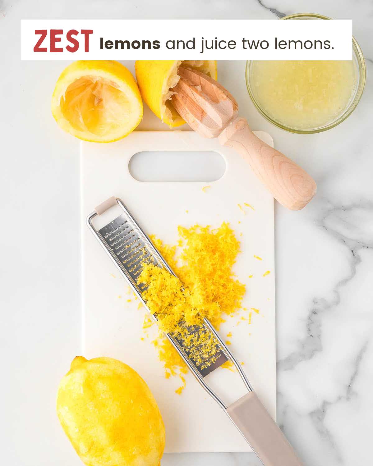 Lemon zest partially covers a zester on a cutting board with a lemon on it. Above the cutting board are juiced lemon halves with a juicer still in one half, next to a bowl of lemon juice.
