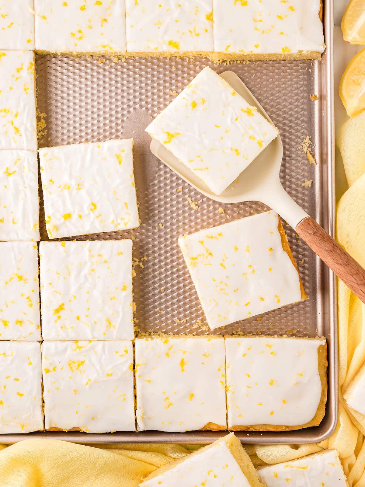 A Glazed German Lemon Sheet Cake with several pieces sliced.