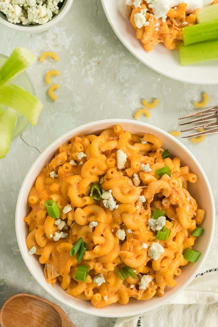 a bowl of freshly cooked buffalo chicken mac and cheese topped with scallions and blue cheese