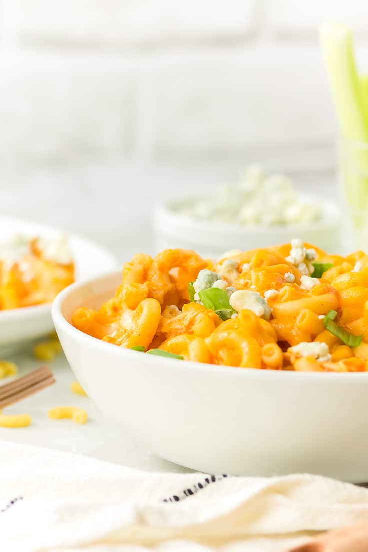 a bowl of freshly cooked mac and cheese with buffalo chicken and topped with crumbled blue cheese