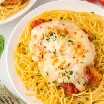 A plate of cheesy Chicken Parmesan spaghetti.