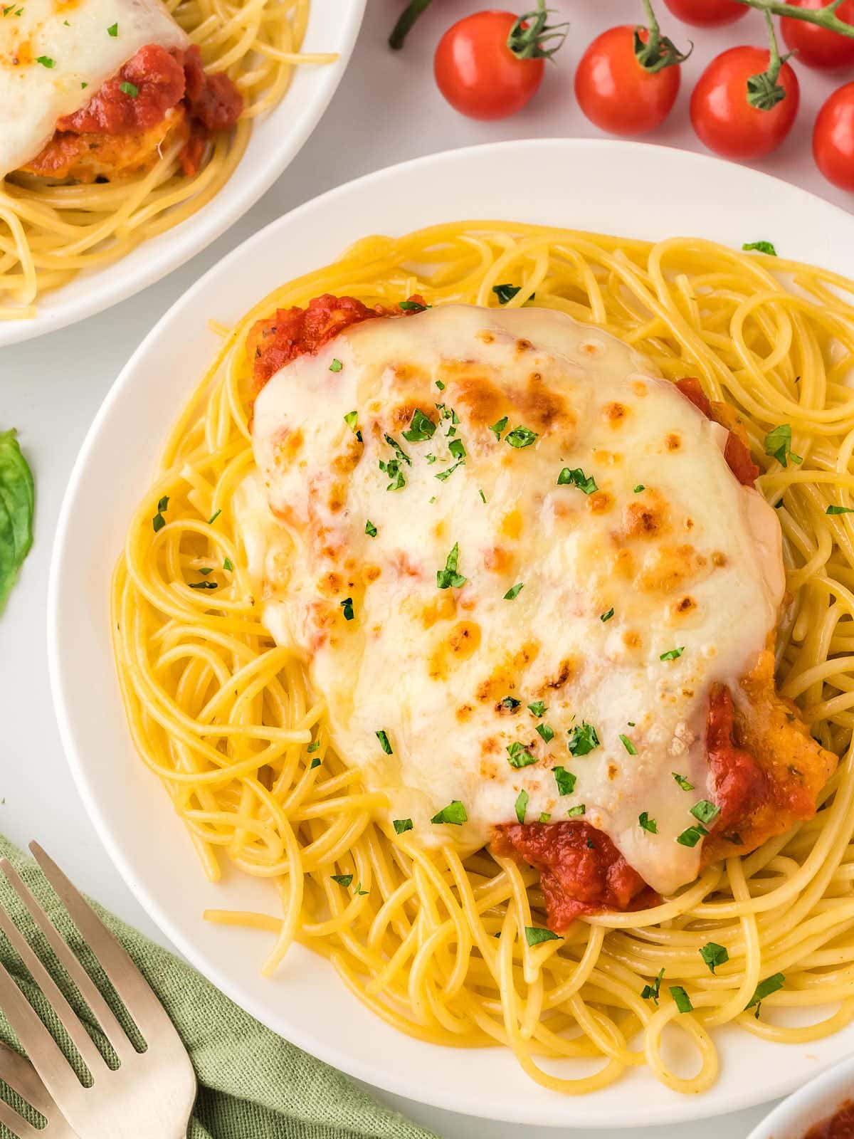 A plate of cheesy Chicken Parmesan spaghetti.