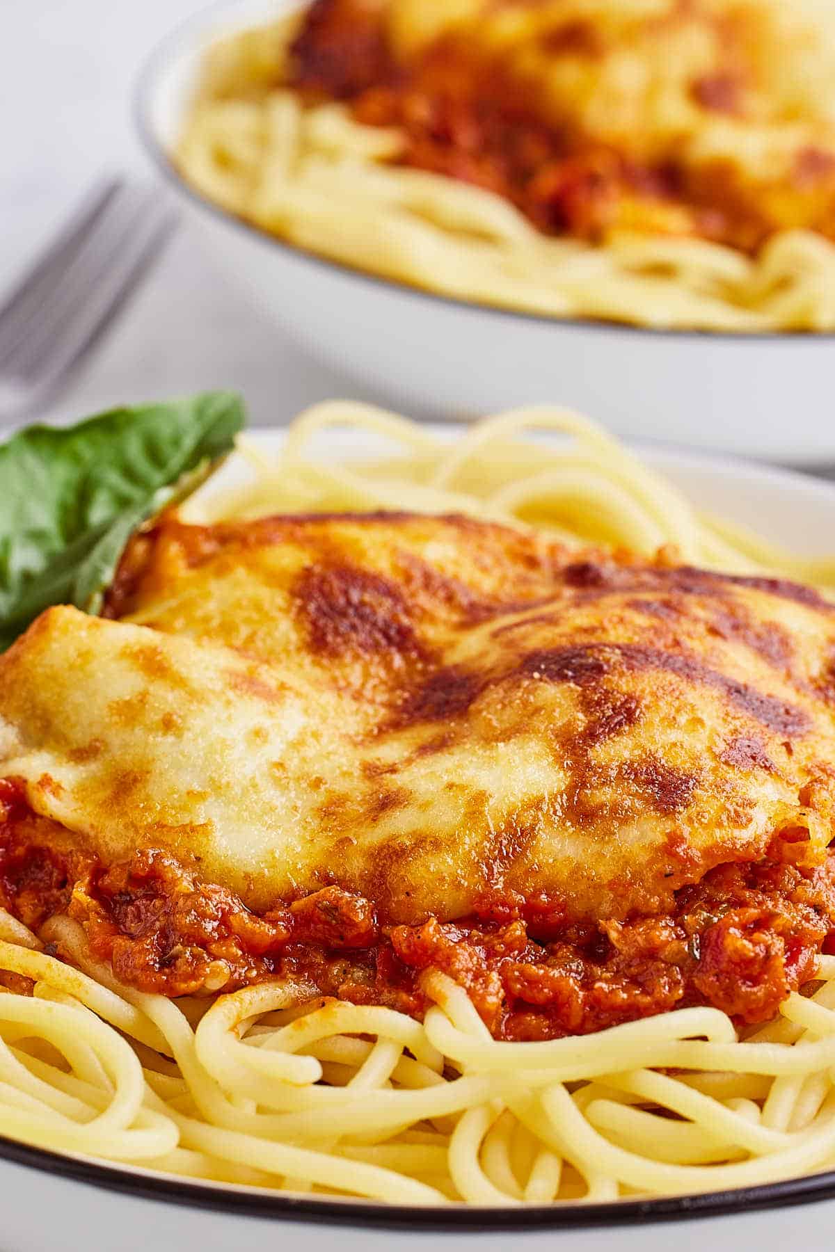 Closeup of a Chicken Parmesan served on spaghetti pasta.