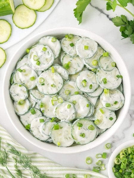 Topdown view of a Creamy German Cucumber Salad served in a white bowl.