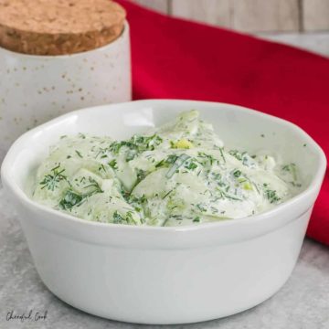 A bowl of creamy cucumber salad in a fresh herb dressing.