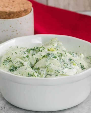 a bowl of creamy cucumber salad in a fresh herb dressing
