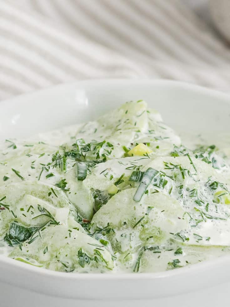 Creamy cucumber salad served in a white bowl