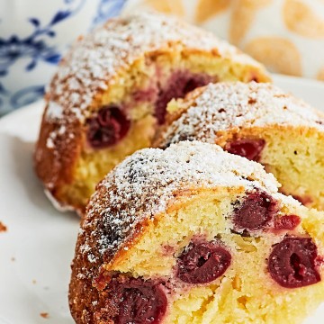 A slice of German Cherry Bundt Cake with powdered sugar on a plate.