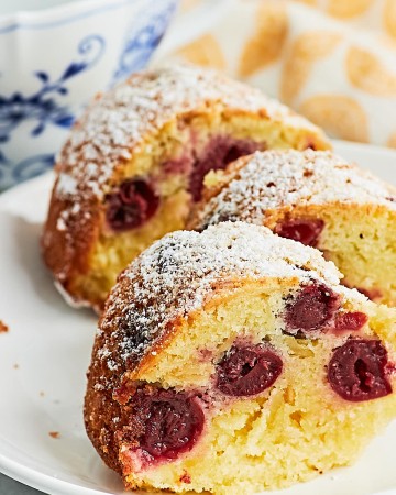 A slice of German Cherry Bundt Cake with powdered sugar on a plate.