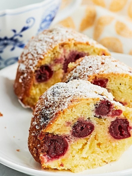 A slice of German Cherry Bundt Cake with powdered sugar on a plate.