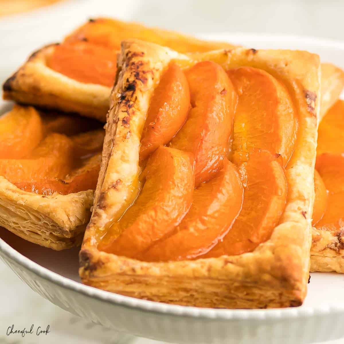 4 apricot tarts on a white cake stand