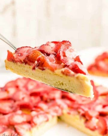 a slice of freshly bake Erdbeerkuchen (German Strawberry Torte) with a side of whipped cream