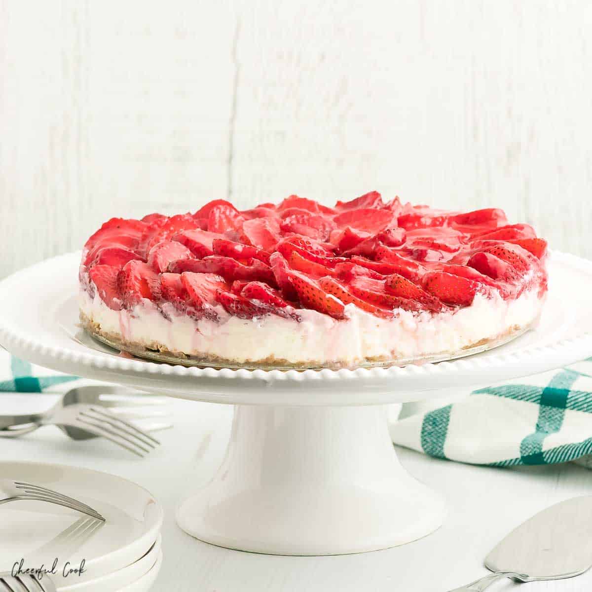 No bake Strawberry Cheesecake on a white cake stand.