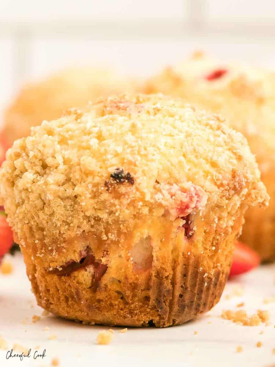 a close up of a single, freshly baked strawberry streusel muffin
