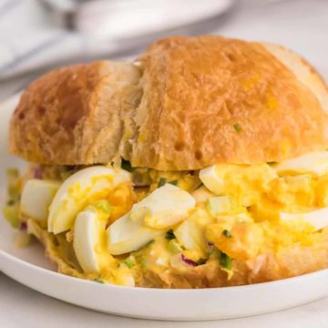 Egg Salad served in a croissant on a white plate.