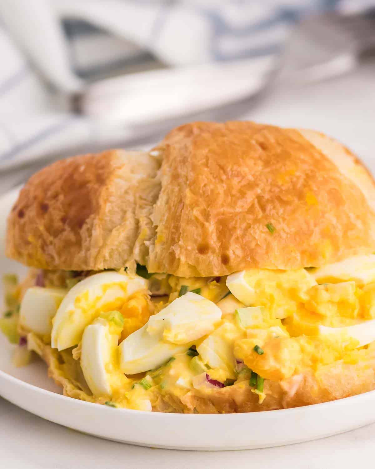 egg salad in a croissant on a white plate