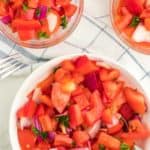 A bowl of freshly made German tomato salad (Tomatensalat) also served in two small glass bowls as a side salad.
