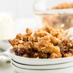 freshly baked apple crisp served on a white place with vanilla ice cream