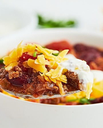 A forkful of Ground Beef Chili with sour cream on cheese.