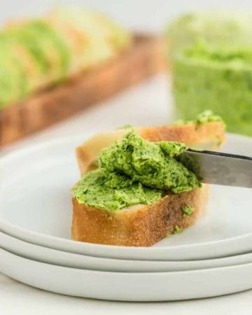 parsley butter on a slice of baguette served on a white plate