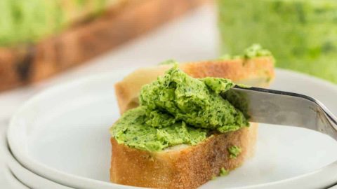 parsley butter on a slice of baguette served on a white plate