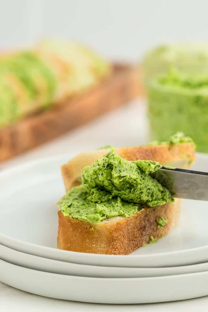 spreading parsley butter onto a slice of baguette with a butter knife