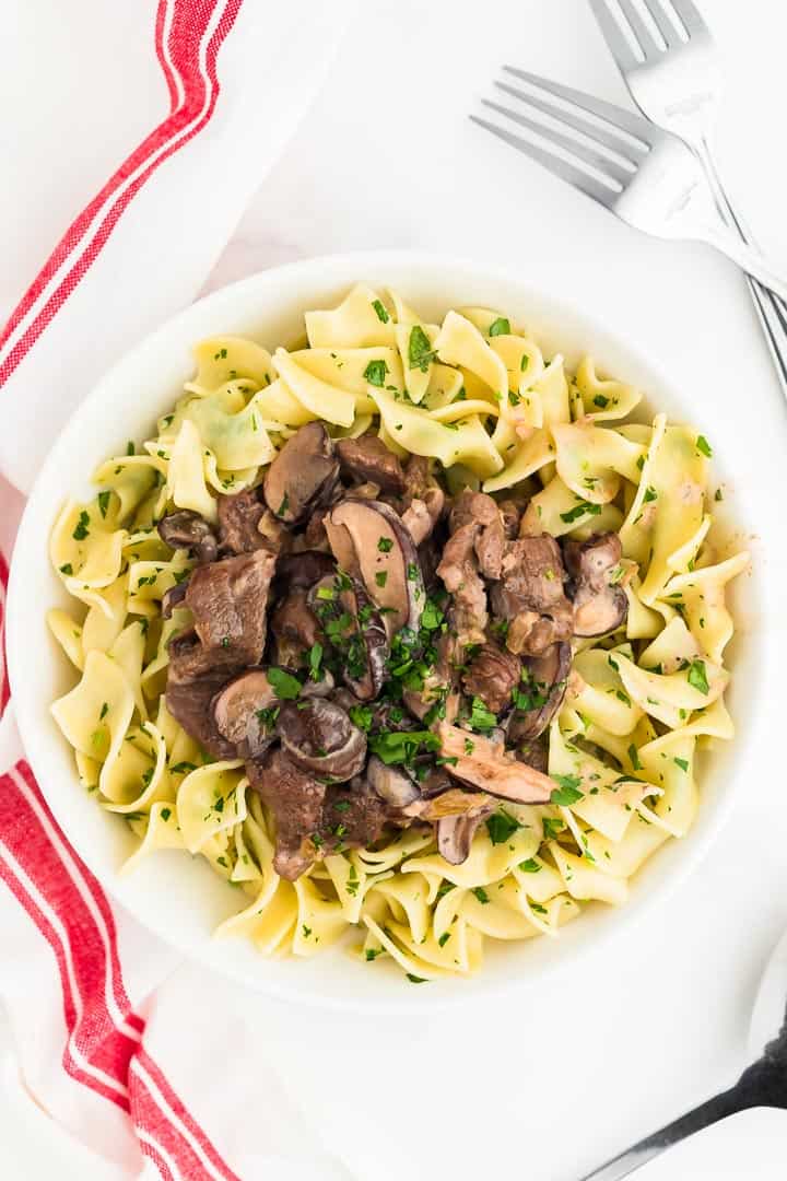 beef stroganoff served over parsley egg noodles in white pasta bowl
