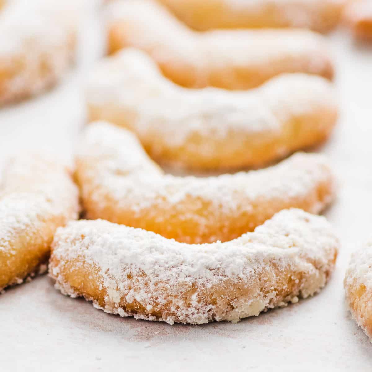 Closeup of a row of almond crescent cookies.