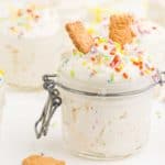 mason jar full of dunkaroo dip topped with two graham cracker animal cookies