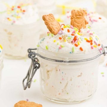 A mason jar full of Dunkaroo Dip topped with two graham cracker animal cookies.