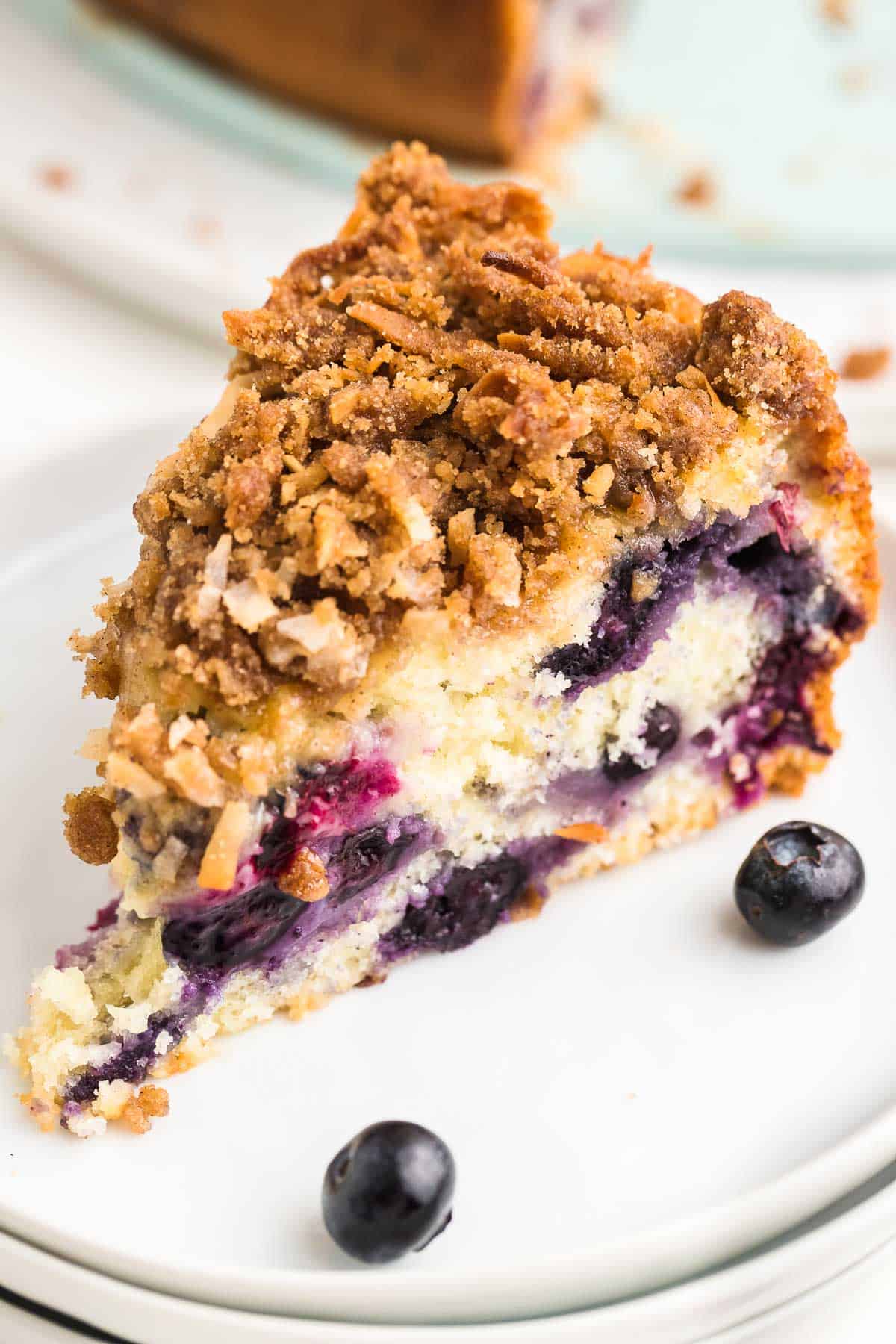 A slice of freshly baked Blueberry Coffee Cake on a white plate.