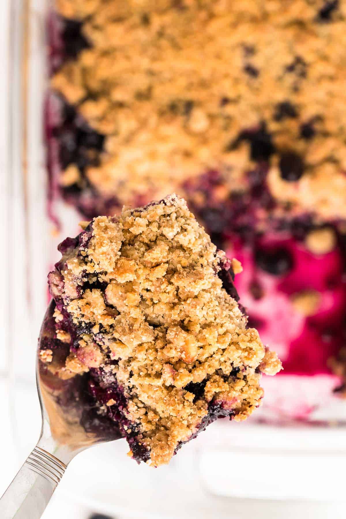 a slice of freshly baked blueberry crisp on a serving spoon