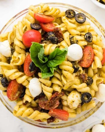 freshly made pesto pasta salad in a glass serving bowl