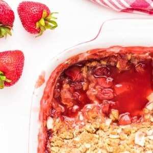 strawberry crumble in white baking dish with two sliced removed