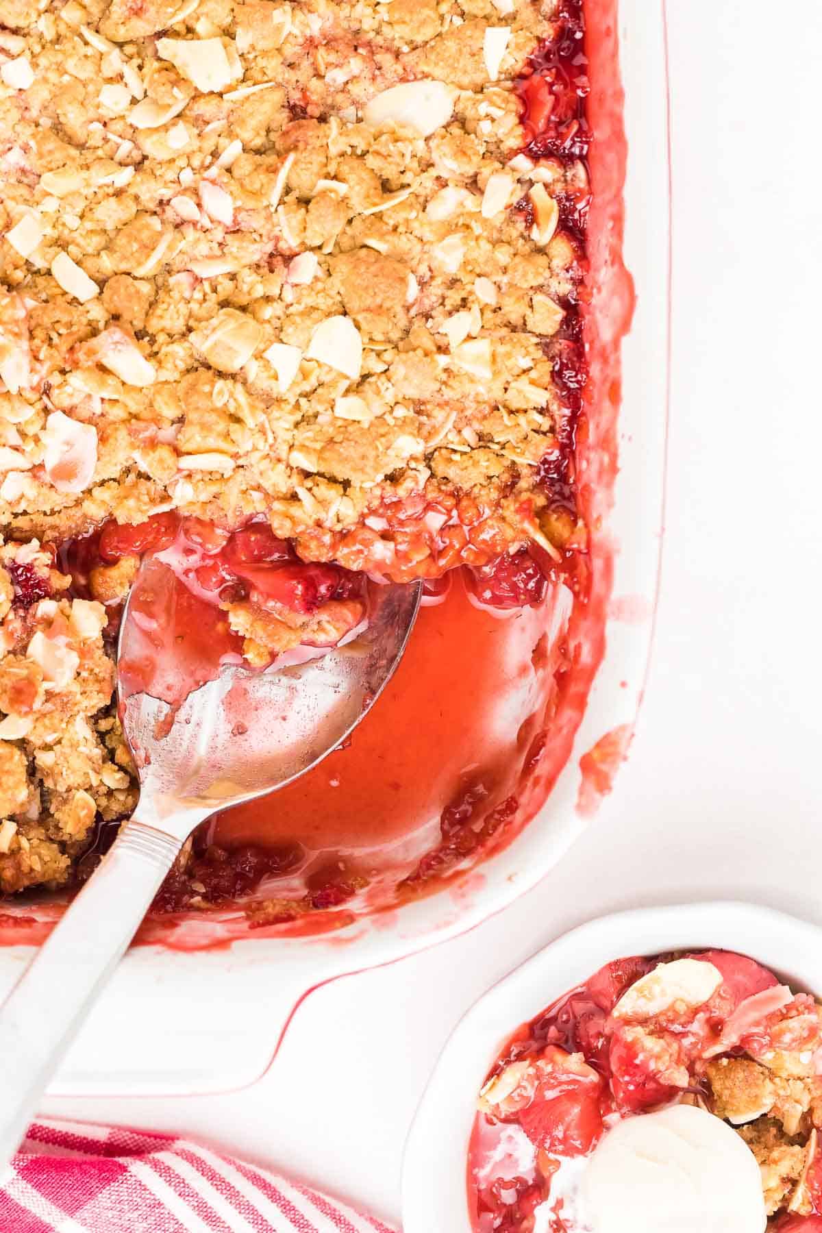 strawberry crisp in baking dish with a serving spoon