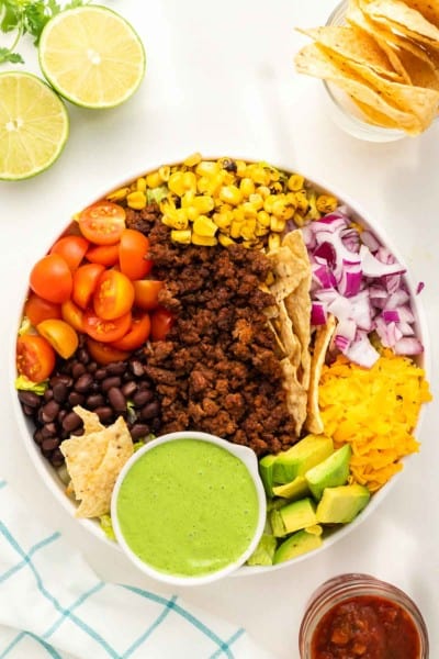 beef taco salad in a white bowl served with a homemade creamy cilantro dressing