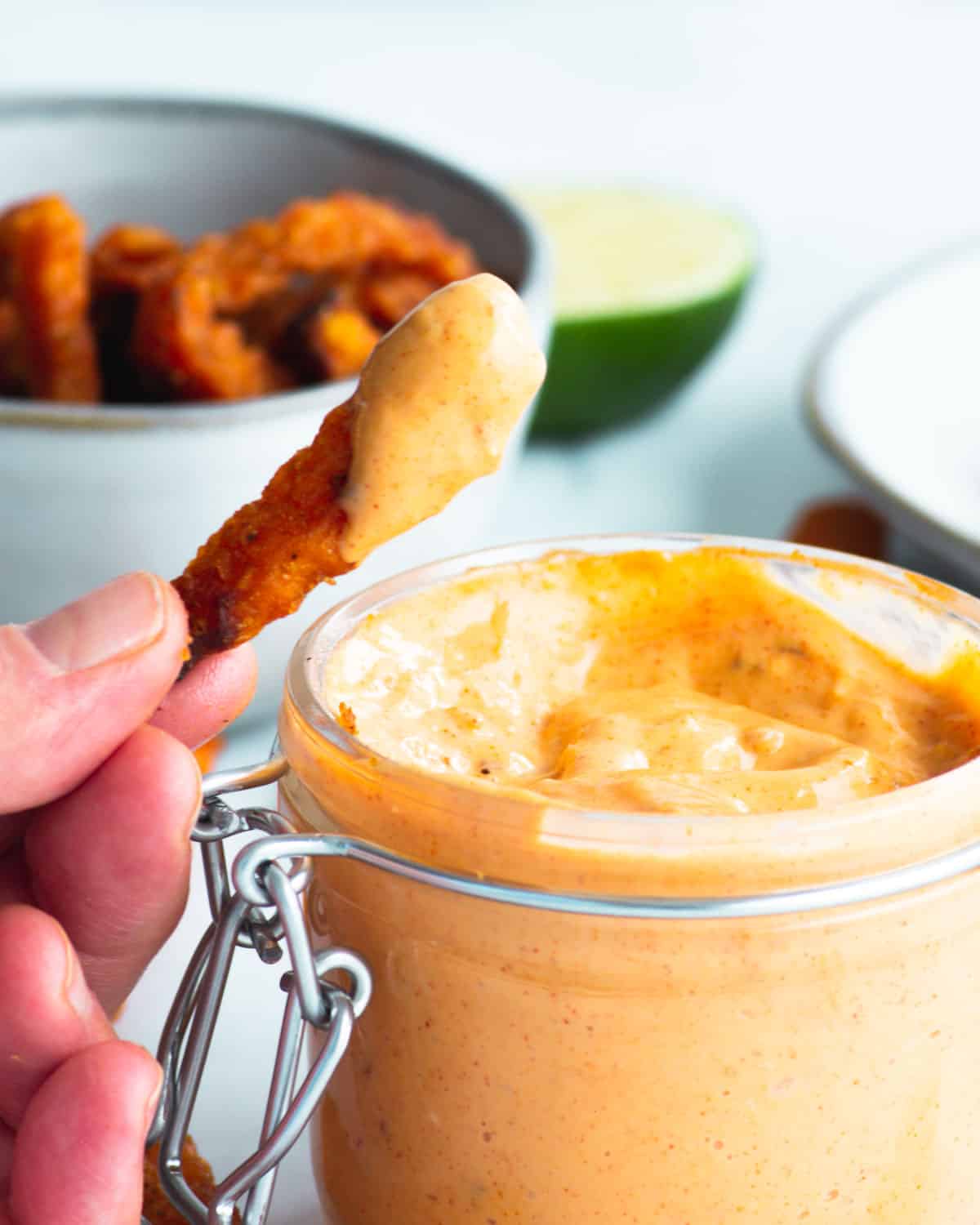 dipping a sweet potato fries into freshly made mayo dip