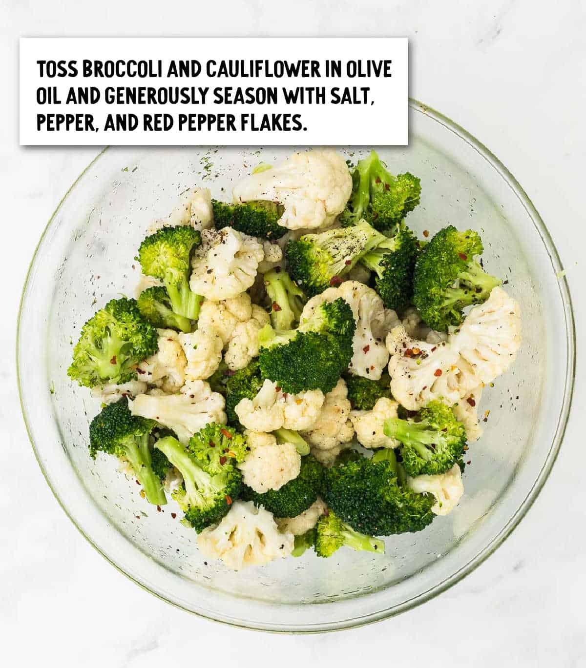 Broccoli and Cauliflower tossed in olive oil and seasoned in a large glass bowl.