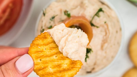 closeup of a wheat cracker dipping in smoked salmon dip