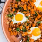 Closeup of a skillet with sweet potato hash and fried eggs.